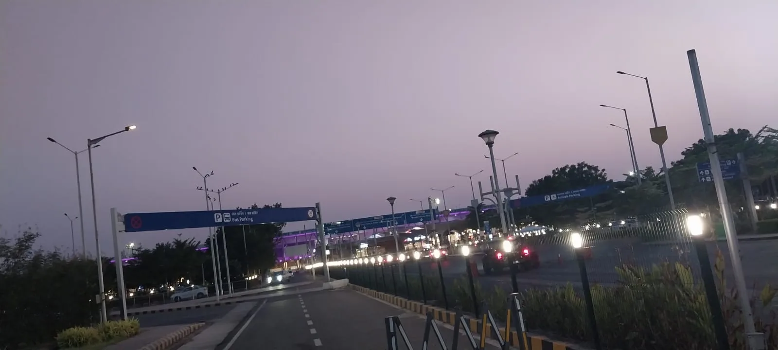 Nexus Lumos lit fence line along the SVPIA Ahmedabad access road at dusk with traffic passing